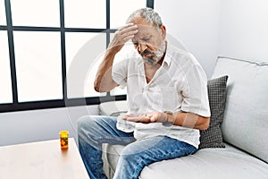 Senior grey-haired man taking pill for headache at home