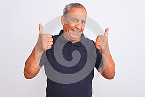 Senior grey-haired man wearing black casual polo standing over isolated white background success sign doing positive gesture with