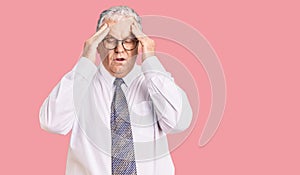 Senior grey-haired man wearing business clothes with hand on head for pain in head because stress