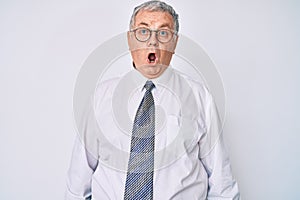 Senior grey-haired man wearing business clothes scared and amazed with open mouth for surprise, disbelief face
