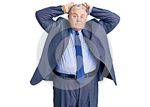 Senior grey-haired man wearing business jacket doing bunny ears gesture with hands palms looking cynical and skeptical