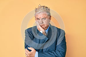 Senior grey-haired man wearing business suit and king crown thinking looking tired and bored with depression problems with crossed