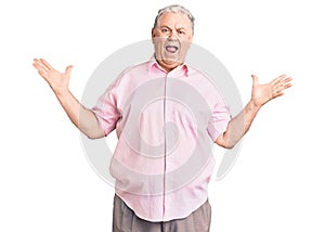 Senior grey-haired man wearing casual clothes celebrating victory with happy smile and winner expression with raised hands