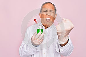 Senior grey-haired scientist man wearing holding sample tube test over pink background annoyed and frustrated shouting with anger,