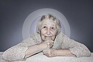 Senior grey haired woman dreaming isolated on blue background