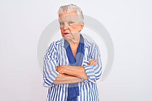 Senior grey-haired woman wearing blue striped shirt standing over isolated white background skeptic and nervous, disapproving
