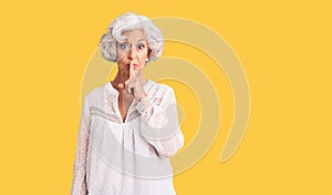 Senior grey-haired woman wearing casual clothes asking to be quiet with finger on lips