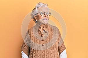 Senior grey-haired woman wearing casual clothes and glasses smiling looking to the side and staring away thinking