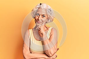 Senior grey-haired woman wearing casual clothes looking confident at the camera smiling with crossed arms and hand raised on chin