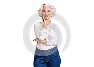 Senior grey-haired woman wearing casual clothes looking confident at the camera smiling with crossed arms and hand raised on chin