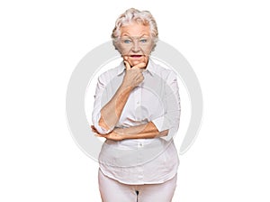 Senior grey-haired woman wearing casual clothes looking confident at the camera smiling with crossed arms and hand raised on chin