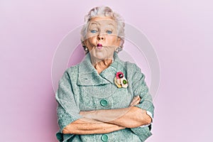 Senior grey-haired woman wearing casual clothes making fish face with mouth and squinting eyes, crazy and comical