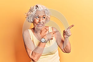 Senior grey-haired woman wearing casual clothes pointing aside worried and nervous with both hands, concerned and surprised