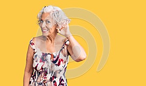 Senior grey-haired woman wearing casual clothes smiling with hand over ear listening an hearing to rumor or gossip