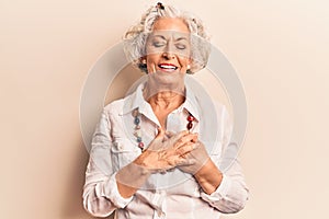 Senior grey-haired woman wearing casual clothes smiling with hands on chest with closed eyes and grateful gesture on face