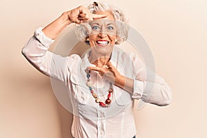 Senior grey-haired woman wearing casual clothes smiling making frame with hands and fingers with happy face