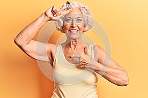 Senior grey-haired woman wearing casual clothes smiling making frame with hands and fingers with happy face