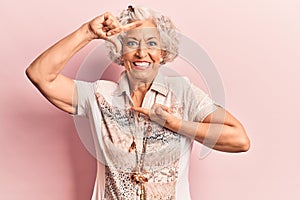 Senior grey-haired woman wearing casual clothes smiling making frame with hands and fingers with happy face