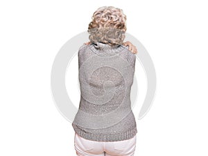 Senior grey-haired woman wearing casual winter sweater hugging oneself happy and positive from backwards