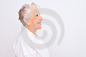 Senior grey-haired woman wearing elegant shirt standing over isolated white background looking to side, relax profile pose with