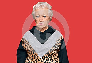 Senior grey-haired woman wearing sportswear with serious expression on face