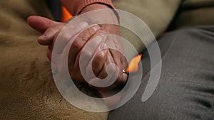 Senior hands holding in front of the fireplace - old age concept