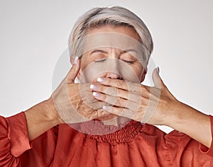Senior, hands and mouth of an elderly woman covering her teeth or lips with hand against a grey studio background