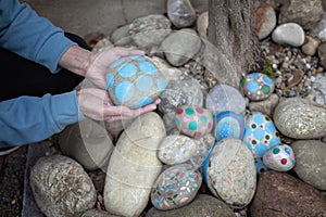 Senior hands with a painted rock among colorful stones.