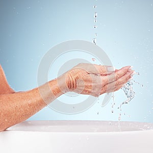 Senior hands, water and wash for clean hygiene, fresh minerals or splash against a studio background. Hand of elderly