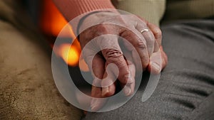 Senior hands of woman and man in front of the fireplace - comforting each other at old age