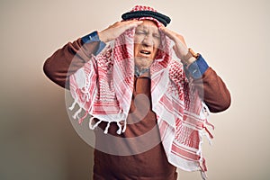 Senior handsome arab man wearing keffiyeh standing over isolated white background suffering from headache desperate and stressed