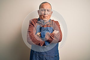 Senior handsome baker man wearing apron standing over isolated white background skeptic and nervous, disapproving expression on