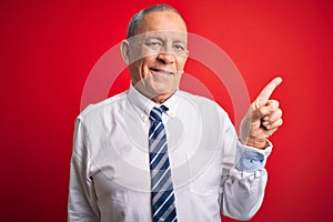 Senior handsome businessman wearing elegant tie standing over isolated red background with a big smile on face, pointing with hand