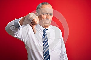 Senior handsome businessman wearing elegant tie standing over isolated red background looking unhappy and angry showing rejection