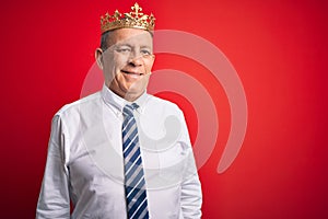 Senior handsome businessman wearing king crown standing over isolated red background with a happy and cool smile on face