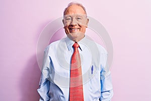 Senior handsome grey-haired businessman wearing elegant tie standing over pink background with a happy and cool smile on face