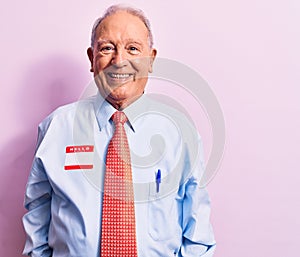 Senior handsome grey-haired businessman wearing tie and shirt with name presentation sticker with a happy and cool smile on face