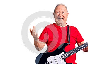 Senior handsome grey-haired man playing electric guitar celebrating victory with happy smile and winner expression with raised