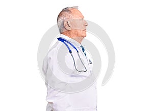 Senior handsome grey-haired man wearing doctor coat and stethoscope looking to side, relax profile pose with natural face and