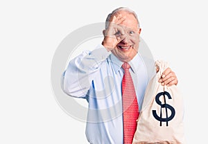 Senior handsome grey-haired man wearing elegant clothes holding money bag smiling happy doing ok sign with hand on eye looking