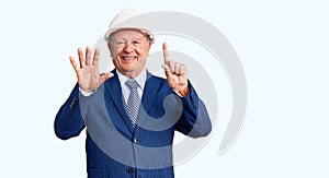 Senior handsome grey-haired man wearing suit and architect hardhat showing and pointing up with fingers number six while smiling