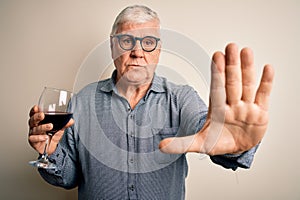 Senior handsome hoary man drinking glass of red wine over isolated white background with open hand doing stop sign with serious