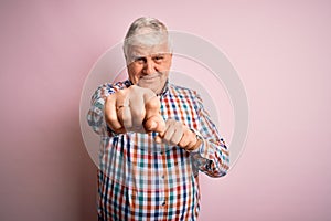 Senior handsome hoary man wearing casual colorful shirt over isolated pink background Punching fist to fight, aggressive and angry