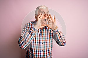 Senior handsome hoary man wearing casual colorful shirt over isolated pink background Shouting angry out loud with hands over