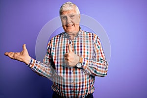 Senior handsome hoary man wearing casual colorful shirt over isolated purple background Showing palm hand and doing ok gesture