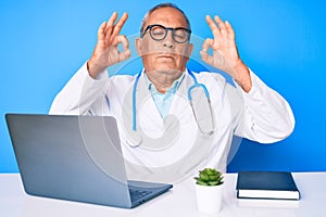 Senior handsome man with gray hair wearing doctor uniform working using computer laptop relax and smiling with eyes closed doing