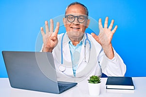 Senior handsome man with gray hair wearing doctor uniform working using computer laptop showing and pointing up with fingers