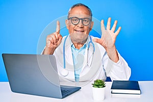 Senior handsome man with gray hair wearing doctor uniform working using computer laptop showing and pointing up with fingers
