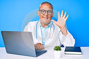 Senior handsome man with gray hair wearing doctor uniform working using computer laptop showing and pointing up with fingers