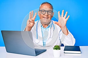 Senior handsome man with gray hair wearing doctor uniform working using computer laptop showing and pointing up with fingers